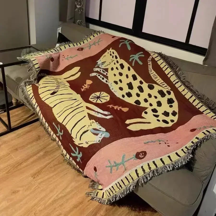 Decorative blanket with animal patterns draped over a couch in a room. Leopard design boho home decor blanket, decorative woven tapestry for living room or bedroom