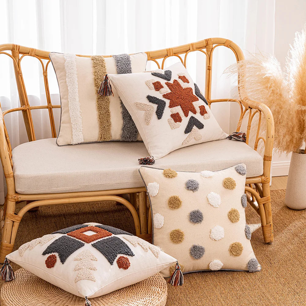 Decorative pillows on a wicker chair with a neutral color scheme. Tufted bohemian throw pillow cover with geometric embroidery and tassels