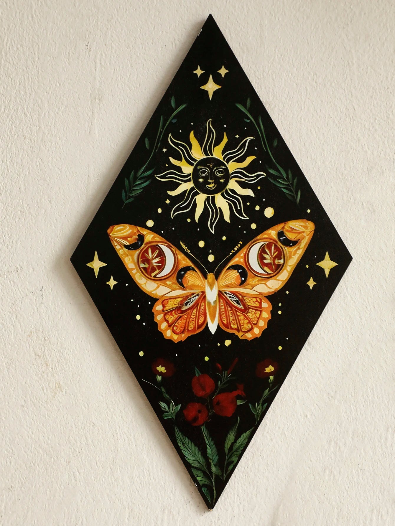 Decorative wall art with a butterfly and sun design on a black background. Rustic colorful wood wall art panel with moon, stars, and butterfly engraving, displayed above a sofa in a boho-styled living room