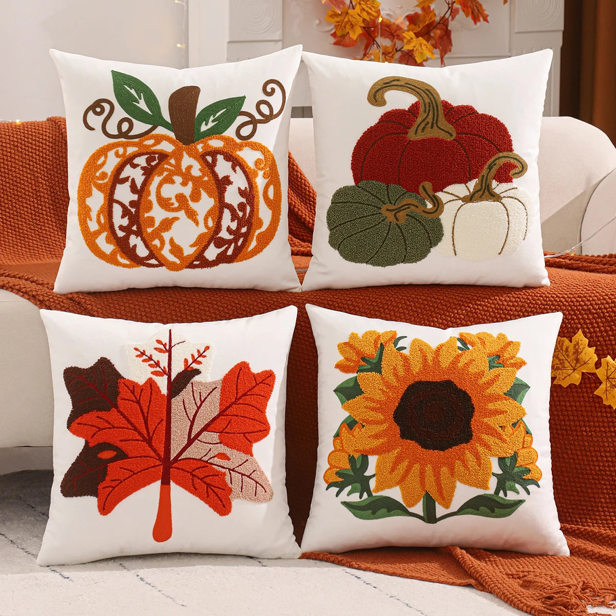 Four decorative pillows with autumn-themed designs on a couch. Velvet pillow cover with embroidered pumpkins, sunflowers, and autumn leaves – cozy fall home décor for sofa or living room.