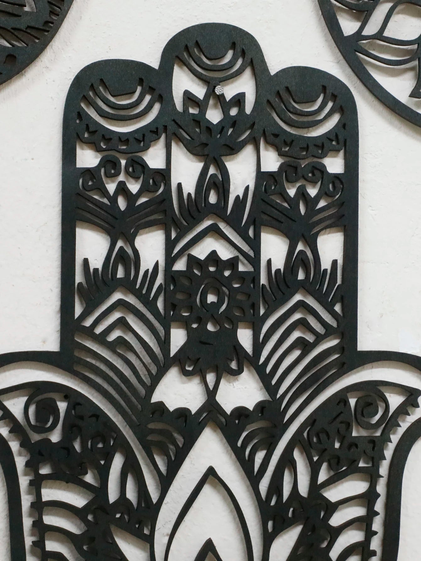 Close-up of evil eye ornament in black hand-shaped wooden wall hanging, ideal for witchy boho home decor or spiritual protection.