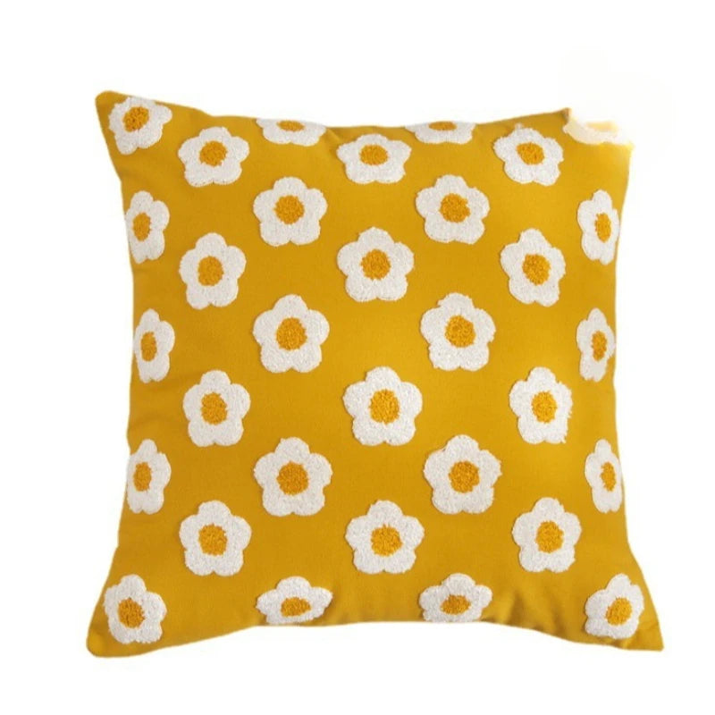 Yellow pillow with white floral patterns on a white background