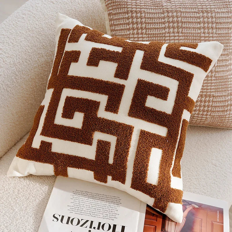 Decorative pillow with brown and white geometric pattern on a beige couch.