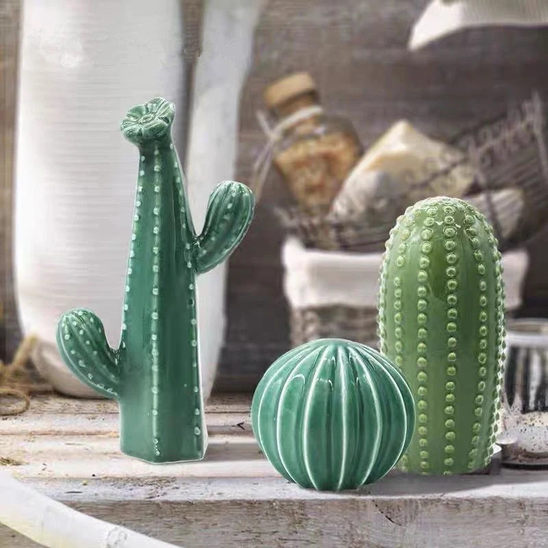Three green ceramic cactus sculptures on a wooden surface with a blurred background. Nordic ceramic cactus ornament for modern home decor