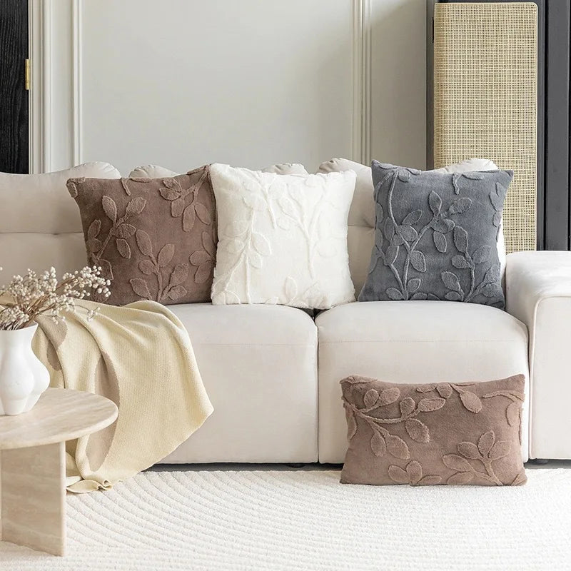 White sofa with decorative pillows and a small table in a living room setting. Modern jacquard leaf throw pillow cover, woven floral decorative cushion for sofa, bed, or living room in neutral and soft tones.