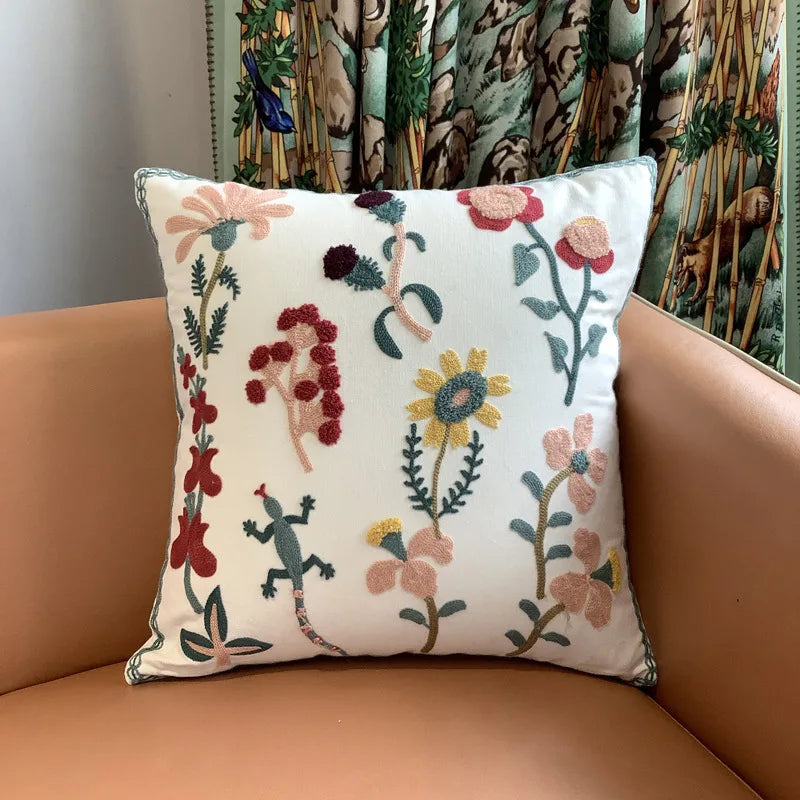 Decorative pillow with floral and lizard embroidery on a brown couch. Nordic lily embroidered throw pillow cover in flannel fabric, floral square cushion case for sofa, bed, and boho home decor