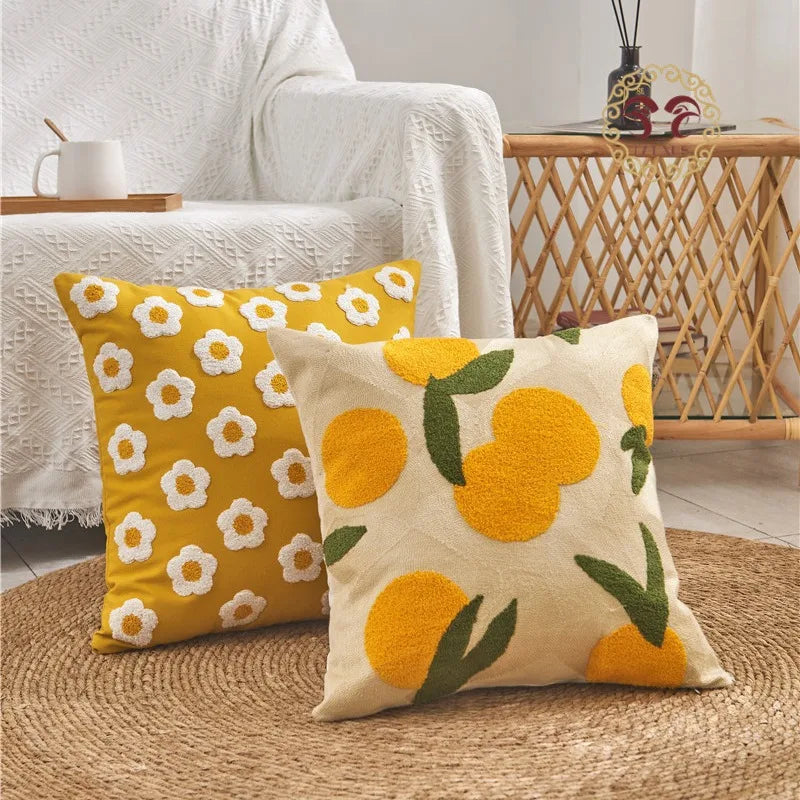 Two decorative pillows with floral and fruit patterns on a textured surface.