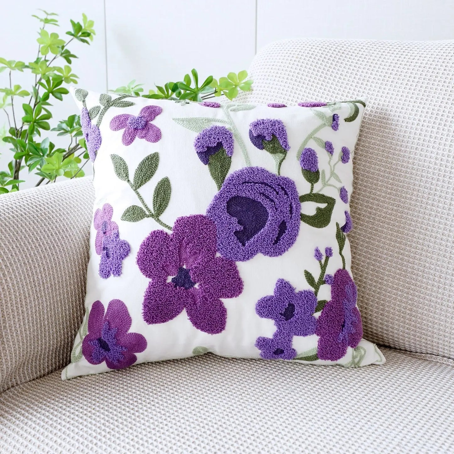 Decorative pillow with purple floral pattern on a beige couch. Floral embroidered throw pillow cover boho decor