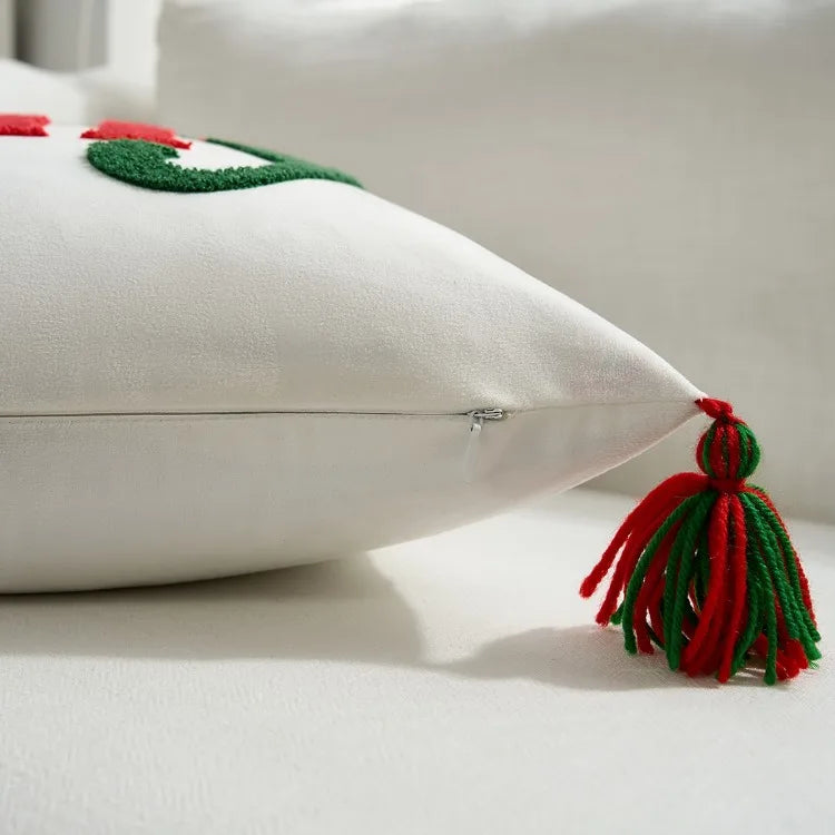 White pillow with a red and green tassel on a light background