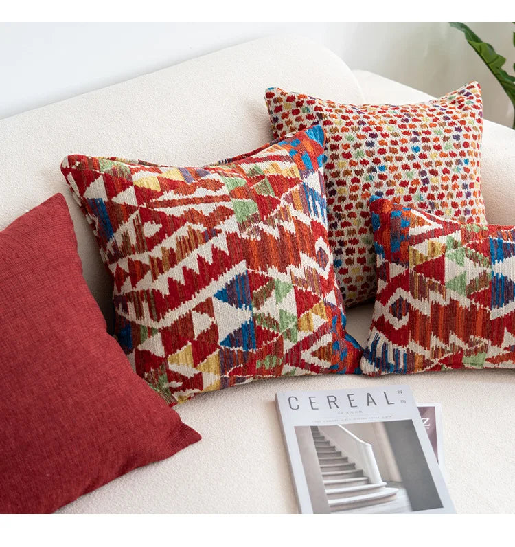 Colorful patterned pillows on a white couch with a magazine underneath. Bohemian Aztec woven pillow cover, geometric jacquard cushion for sofa, bed, or living room decor in neutral cotton blend fabric.
