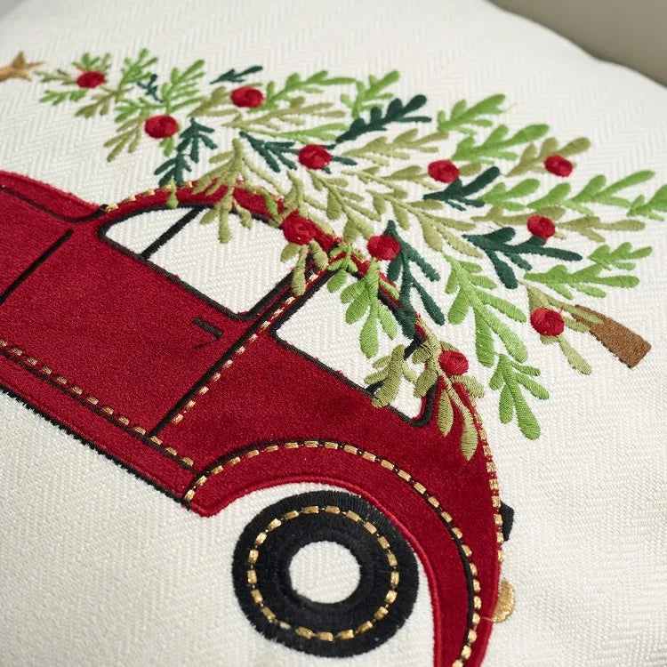 Embroidered design of a red car with Christmas tree branches on a white background