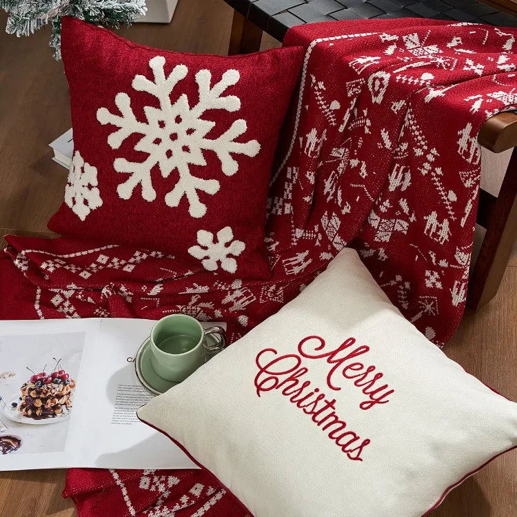 Red and white Christmas-themed pillow with snowflake design and a 'Merry Christmas' pillow on a wooden surface. Christmas gold letter embroidered pillow cover with “Holly Jolly” and snowflake design, soft red and white chenille cushion case for sofa or living room holiday décor.