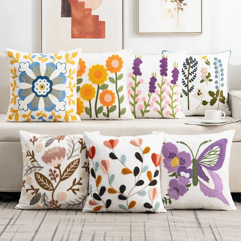 Colorful floral and butterfly patterned pillows on a sofa. Embroidered flower pillow cover, 17.7-inch square canvas cushion case with floral design for sofa, bed, and boho home decor
