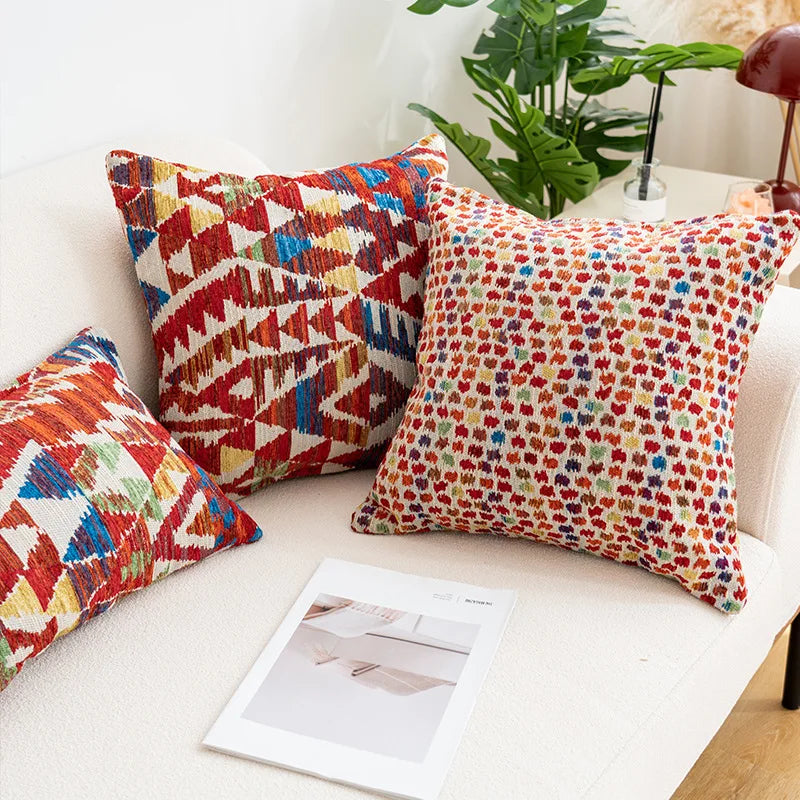 Colorful patterned cushions on a sofa with a magazine underneath. Bohemian Aztec woven pillow cover, geometric jacquard cushion for sofa, bed, or living room decor in neutral cotton blend fabric.