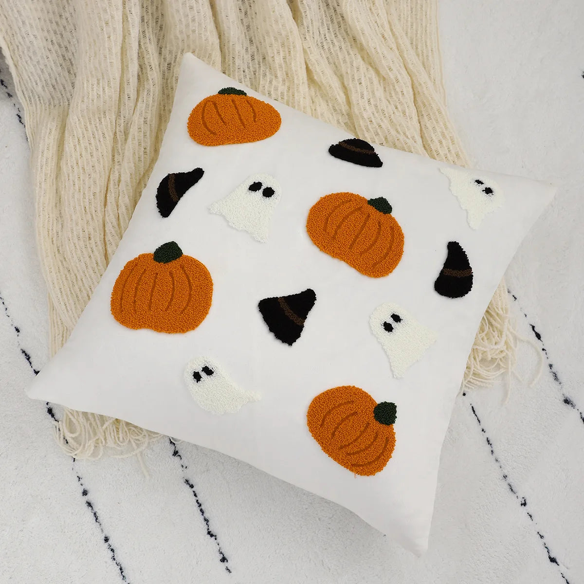 Decorative pillow with pumpkins and ghosts on a textured surface