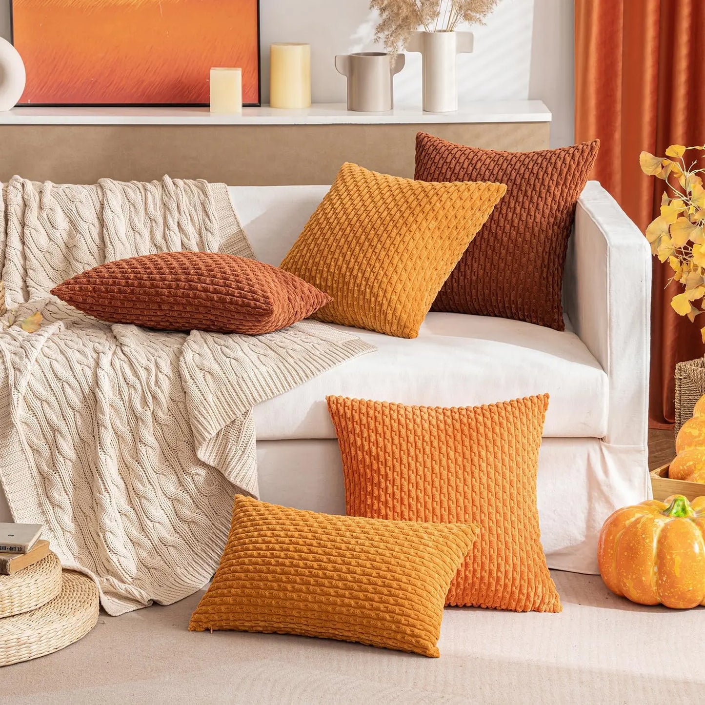 Cozy fall living room with a white sofa adorned with orange and brown textured pillows, a beige throw blanket, and decorative items.