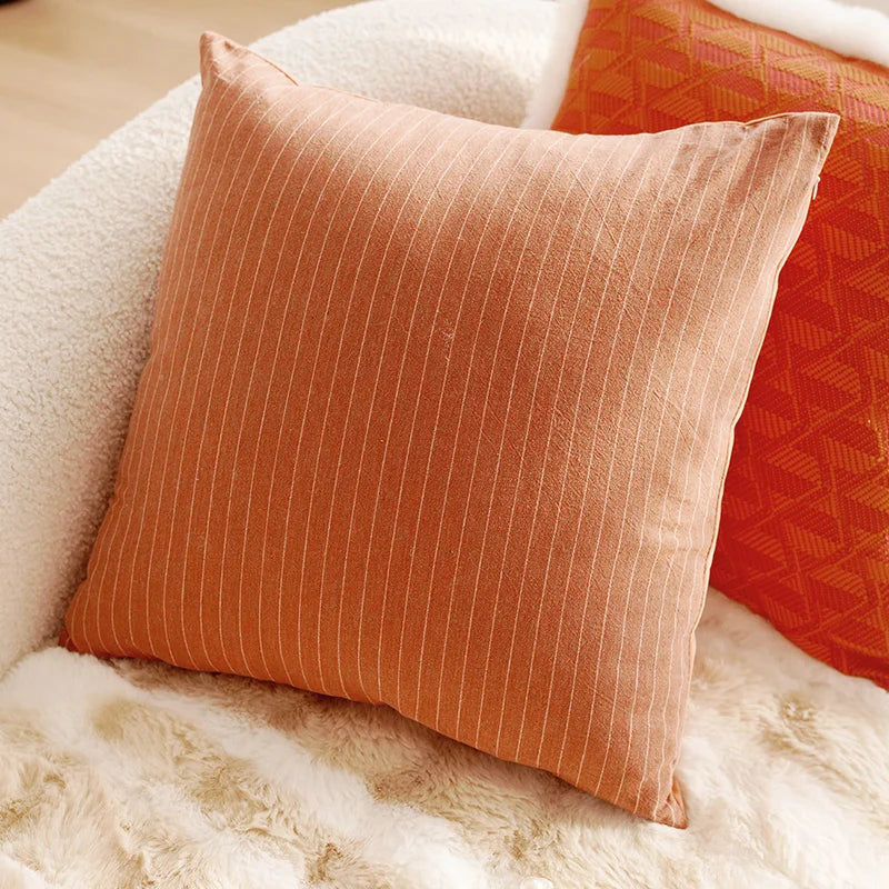 Orange textured pillow on a white surface. Boho Home Decor.