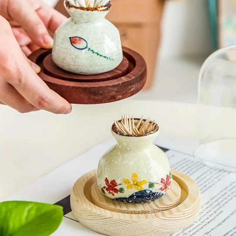 Decorative toothpick holder with floral design on a wooden stand.