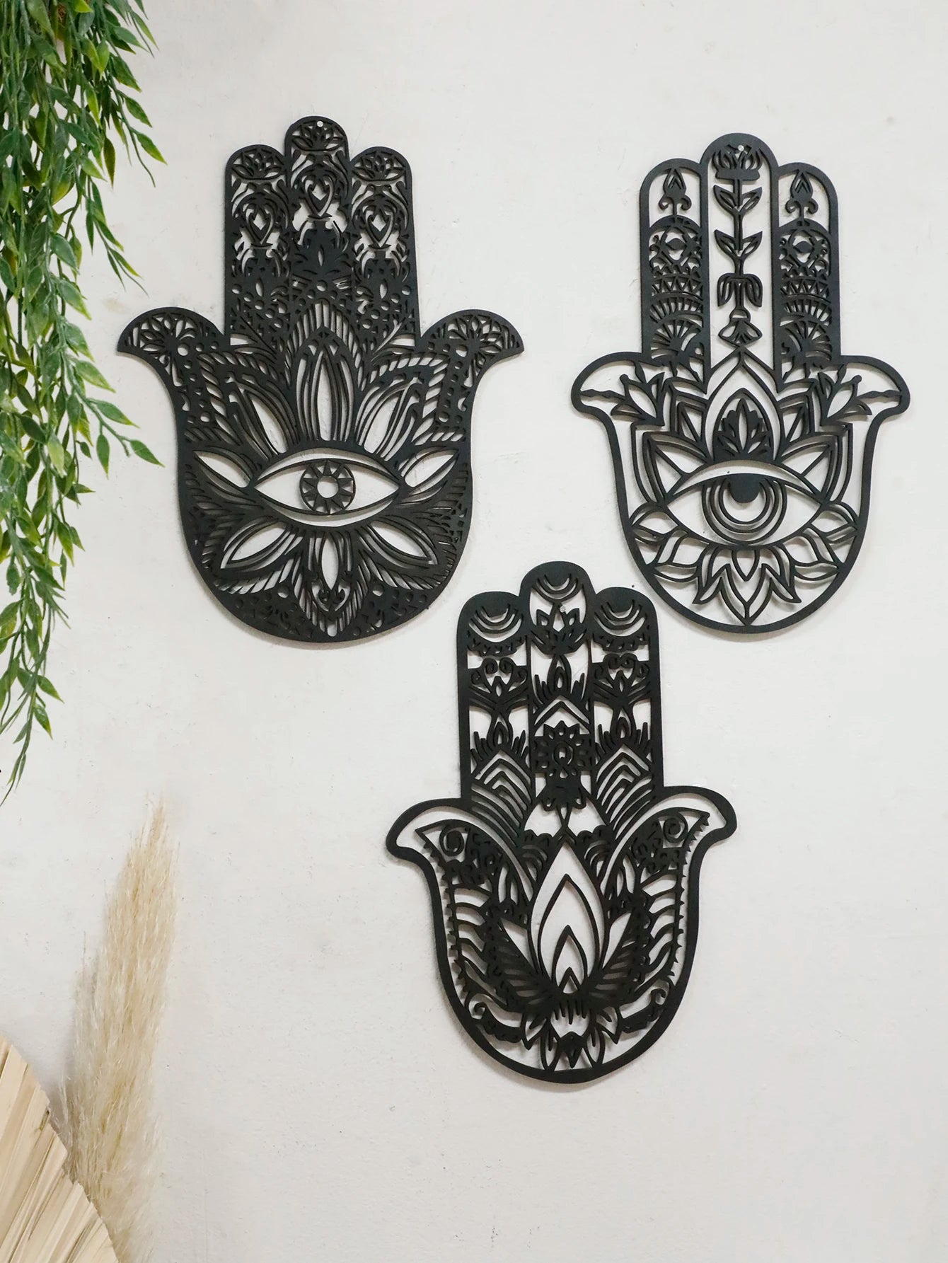 Black hamsa hand-shaped wood wall decor with protective evil eye, photographed against neutral background for alternative boho room styling.