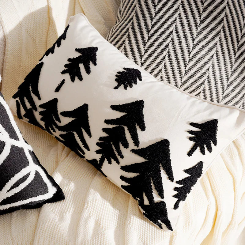 Decorative pillow with black geometric Christmas tree pattern on a beige surface