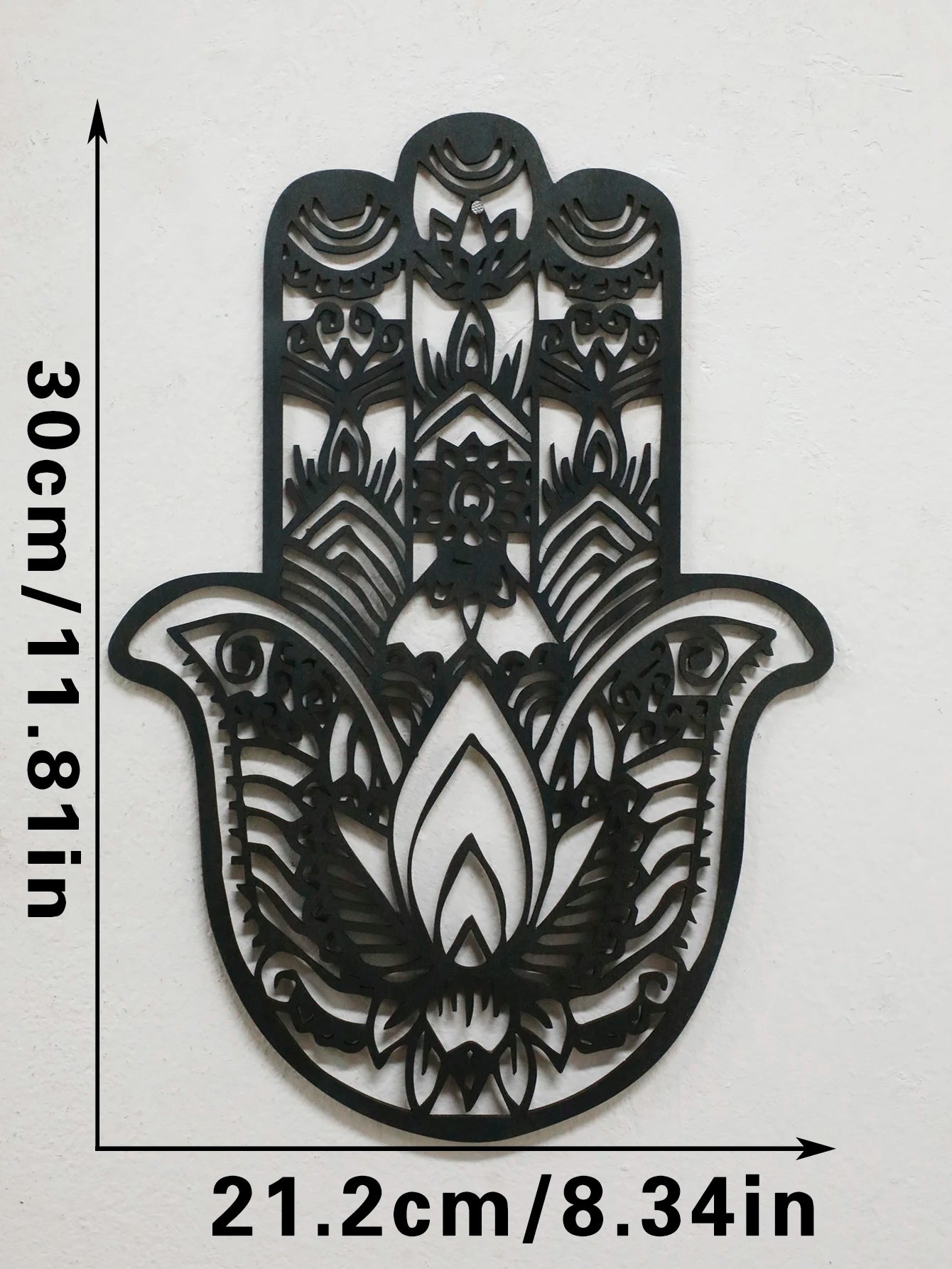Black hamsa hand-shaped wood wall decor with protective evil eye, photographed against neutral background for alternative boho room styling.