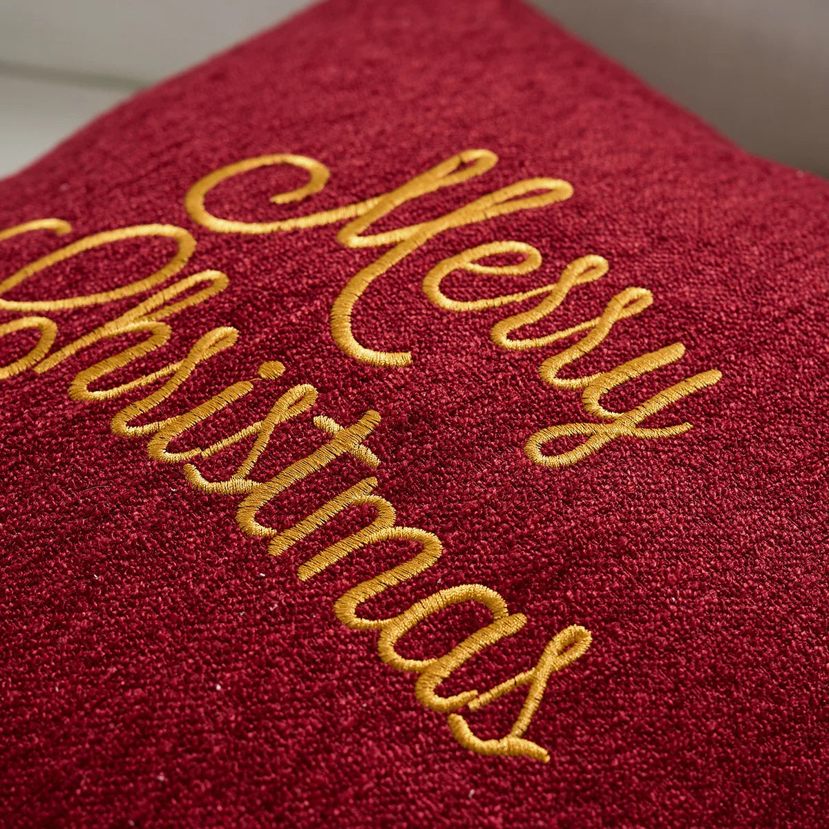 Red fabric with 'Merry Christmas' embroidered in gold thread. Christmas gold letter embroidered pillow cover with “Holly Jolly” and snowflake design, soft red and white chenille cushion case for sofa or living room holiday décor.