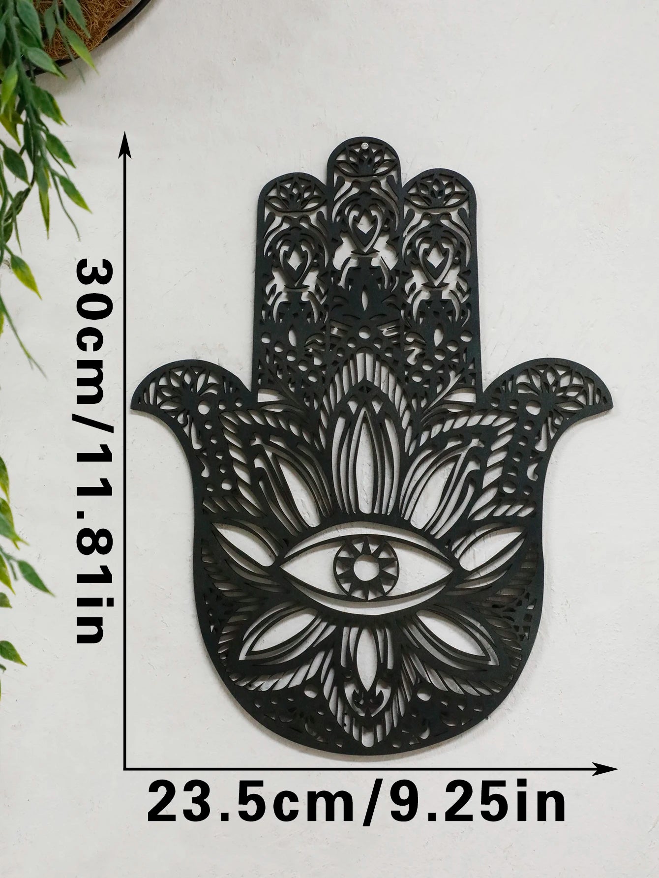 Black hamsa hand-shaped wood wall decor with protective evil eye, photographed against neutral background for alternative boho room styling.