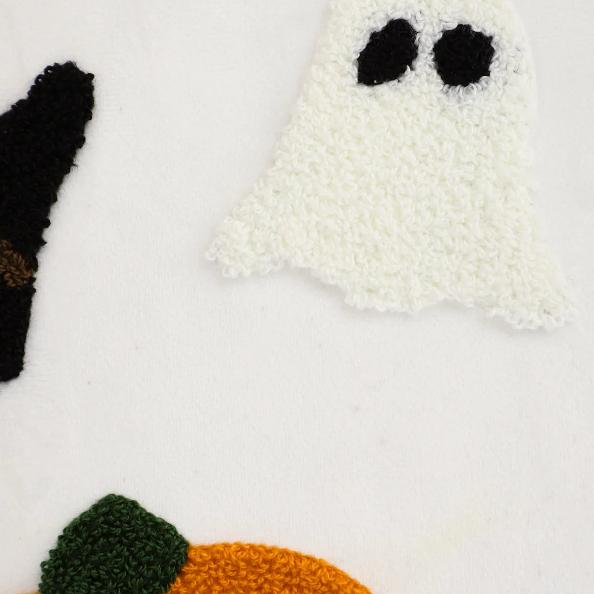 Knitted ghost, black cat, and green leaf on a white background