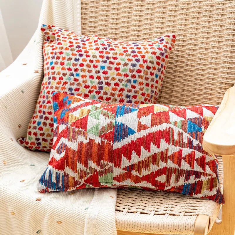 Two colorful patterned pillows on a wicker chair. Bohemian Aztec woven pillow cover, geometric jacquard cushion for sofa, bed, or living room decor in neutral cotton blend fabric.