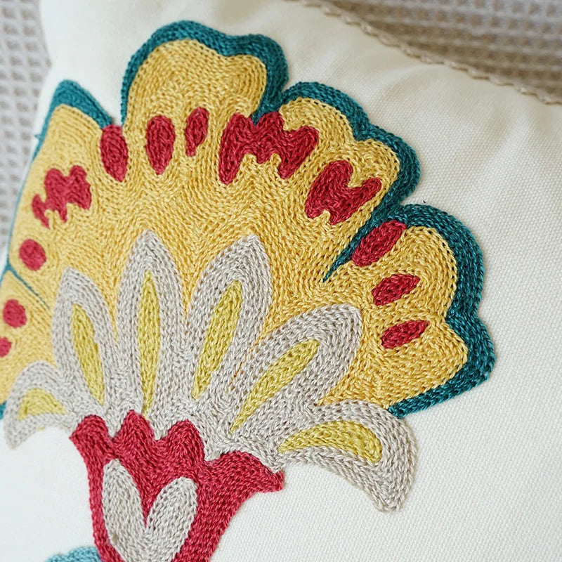 Close-up of a colorful embroidered floral design on a white fabric background. Floral embroidered throw pillow cover boho decor