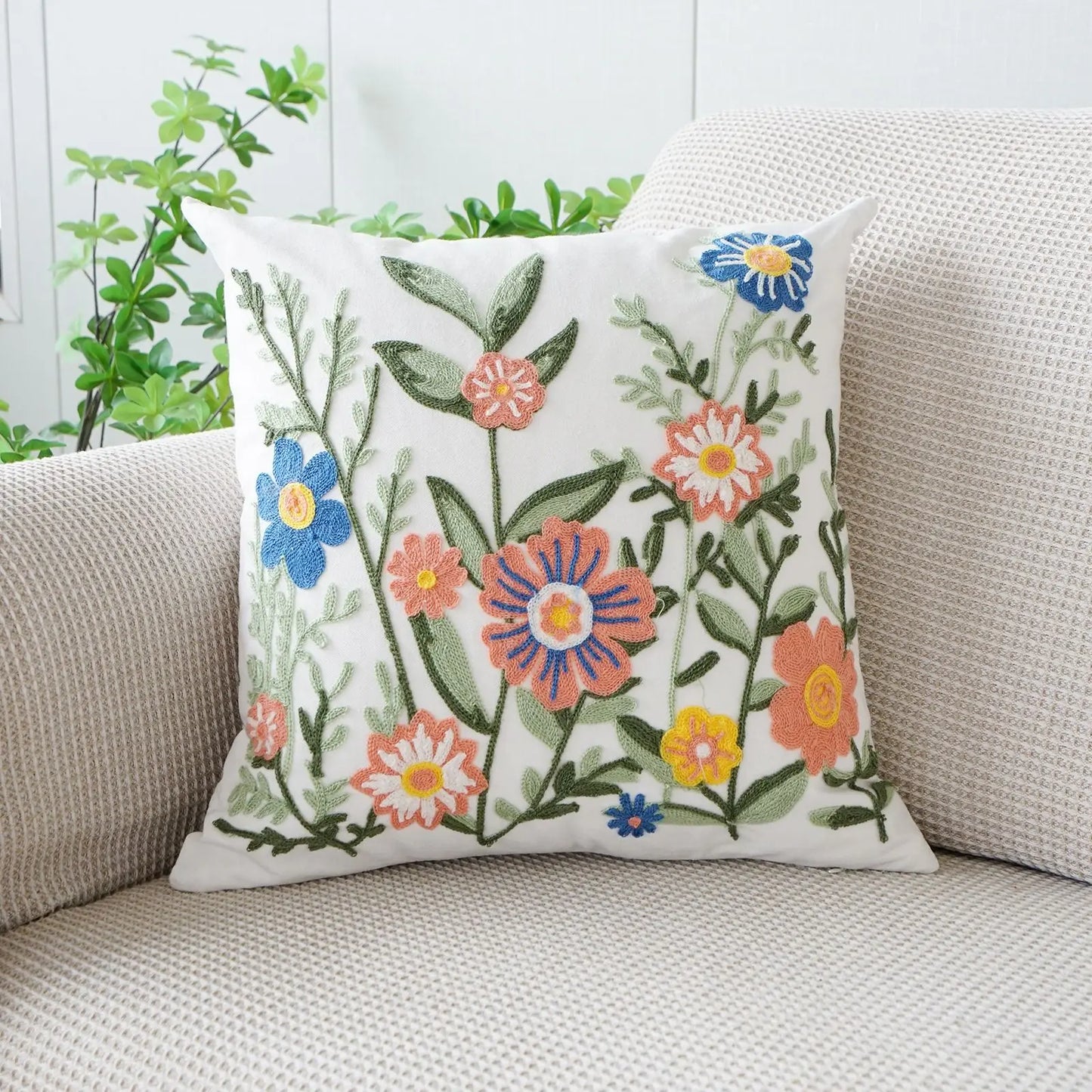 Floral embroidered pillow on a beige couch with a white wall and greenery in the background. Floral embroidered throw pillow cover boho decor