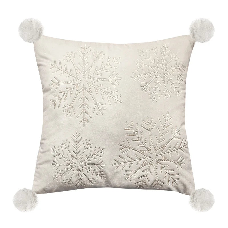 Decorative pillow with snowflake patterns and pom-pom accents on a white background