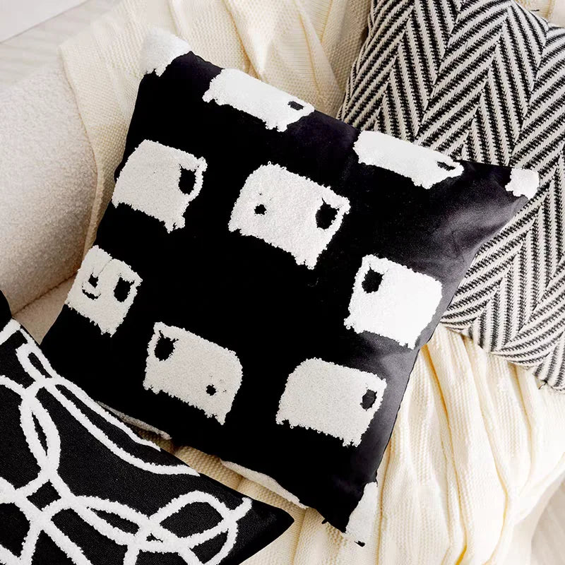 Black pillow with white sheep pattern on a beige sofa