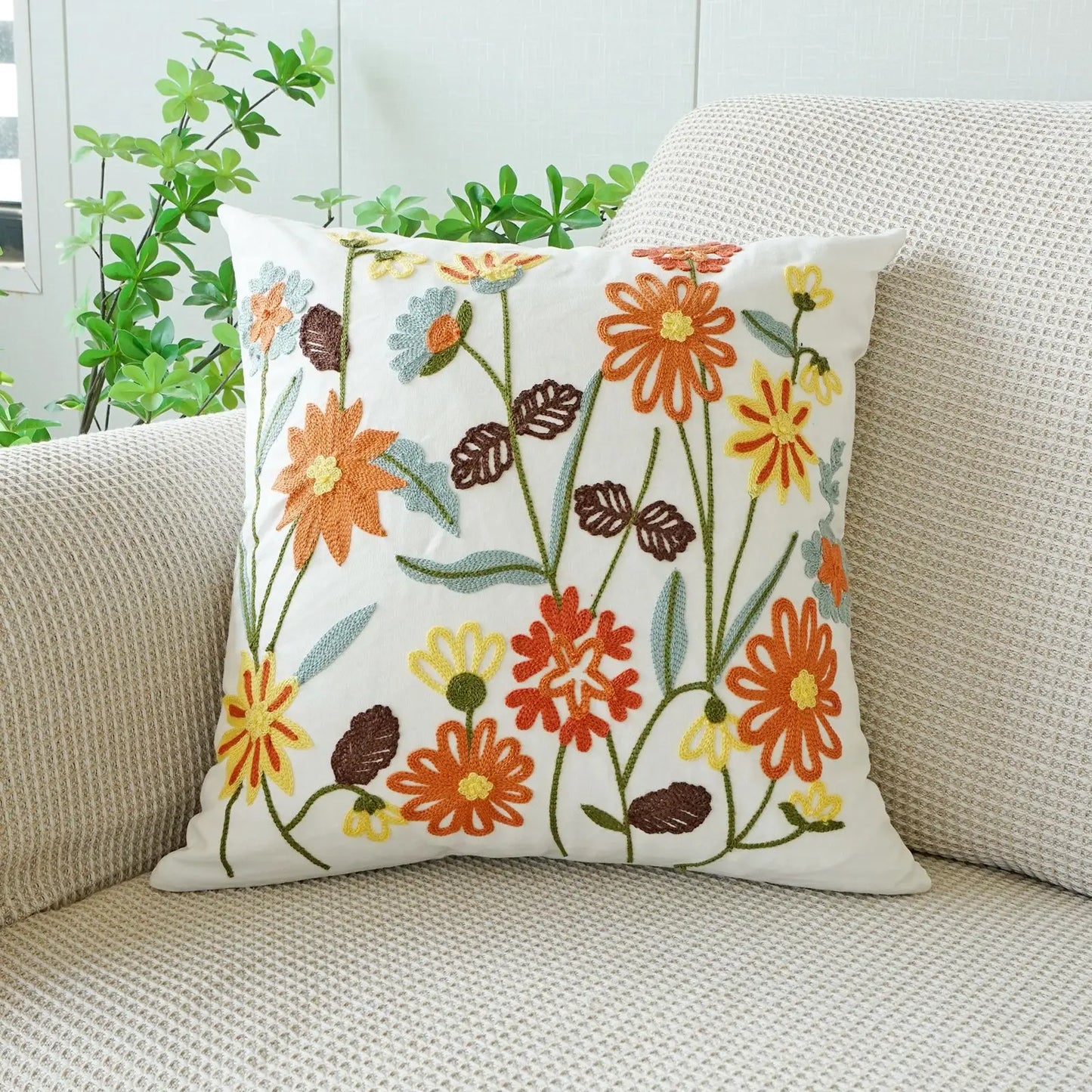 Floral-patterned pillow on a beige couch with plants in the background. Floral embroidered throw pillow cover boho decor