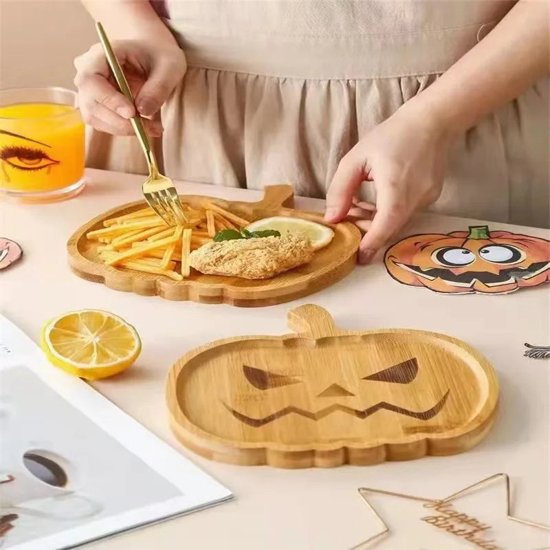 Person using a wooden pumpkin-shaped tray with food on a table. Wooden Halloween serving tray in pumpkin and ghost shapes, rustic snack and dessert plate for party décor and fall entertaining