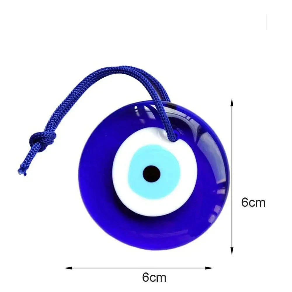 A blue glass Turkish evil eye charm pendant with a blue rope attached, displayed in front of a box.