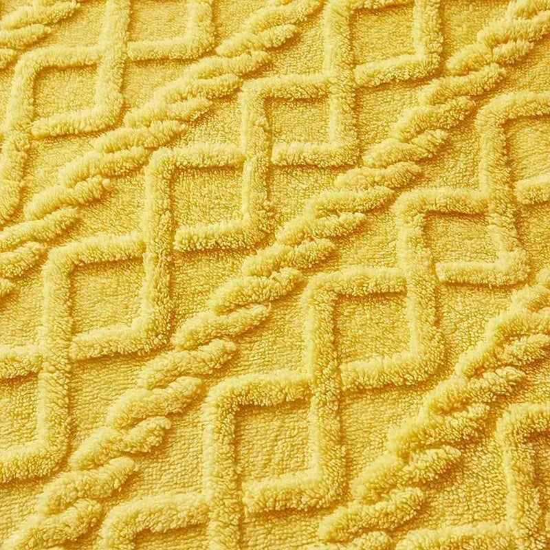 Close-up of a textured yellow fabric with geometric pattern. Soft plush duvet cover and blanket in solid color with striped jacquard design, dual-use artificial cashmere fleece bedding for cozy winter warmth