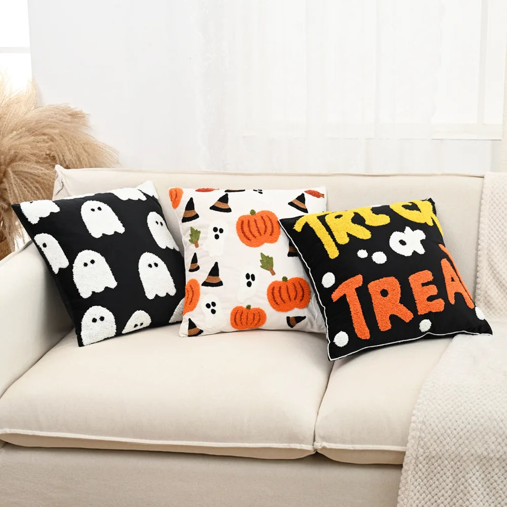 Three Halloween-themed pillows on a beige couch with a white background