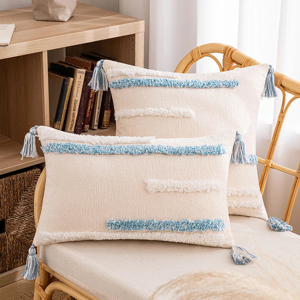 Decorative pillows with blue tassels on a chair next to a bookshelf. Embroidered boho home décor pillowcase cotton blend