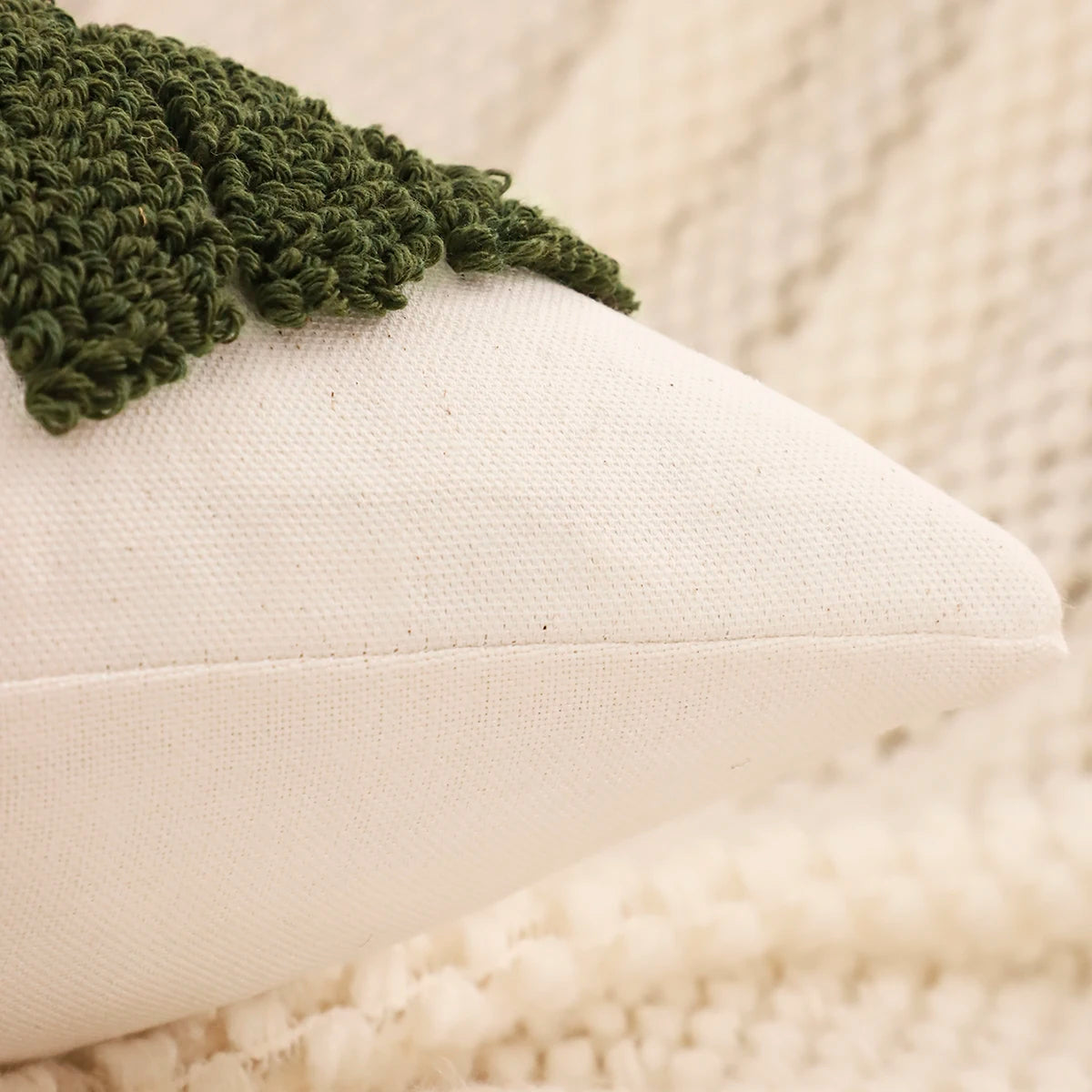 Green knitted blanket on a white cushion with a blurred beige background. Christmas embroidered pillow cover with tufted snowflake and reindeer design in 18x18 inches, festive canvas cushion case for sofa or bed