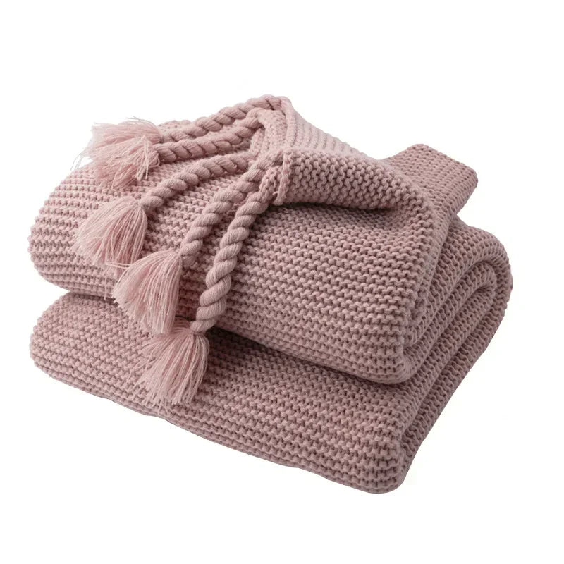 Pink knitted blanket with tassels on a white background