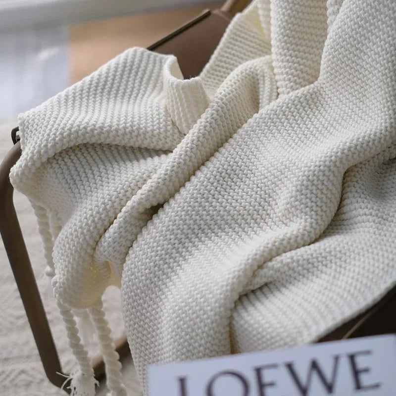 White knitted blanket draped over a chair with a LOEWE label.