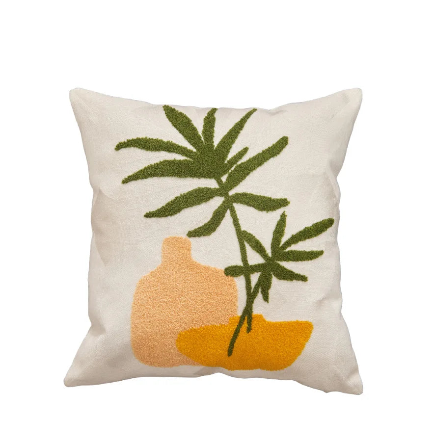 Decorative pillow with green leaves and orange vase on a white background