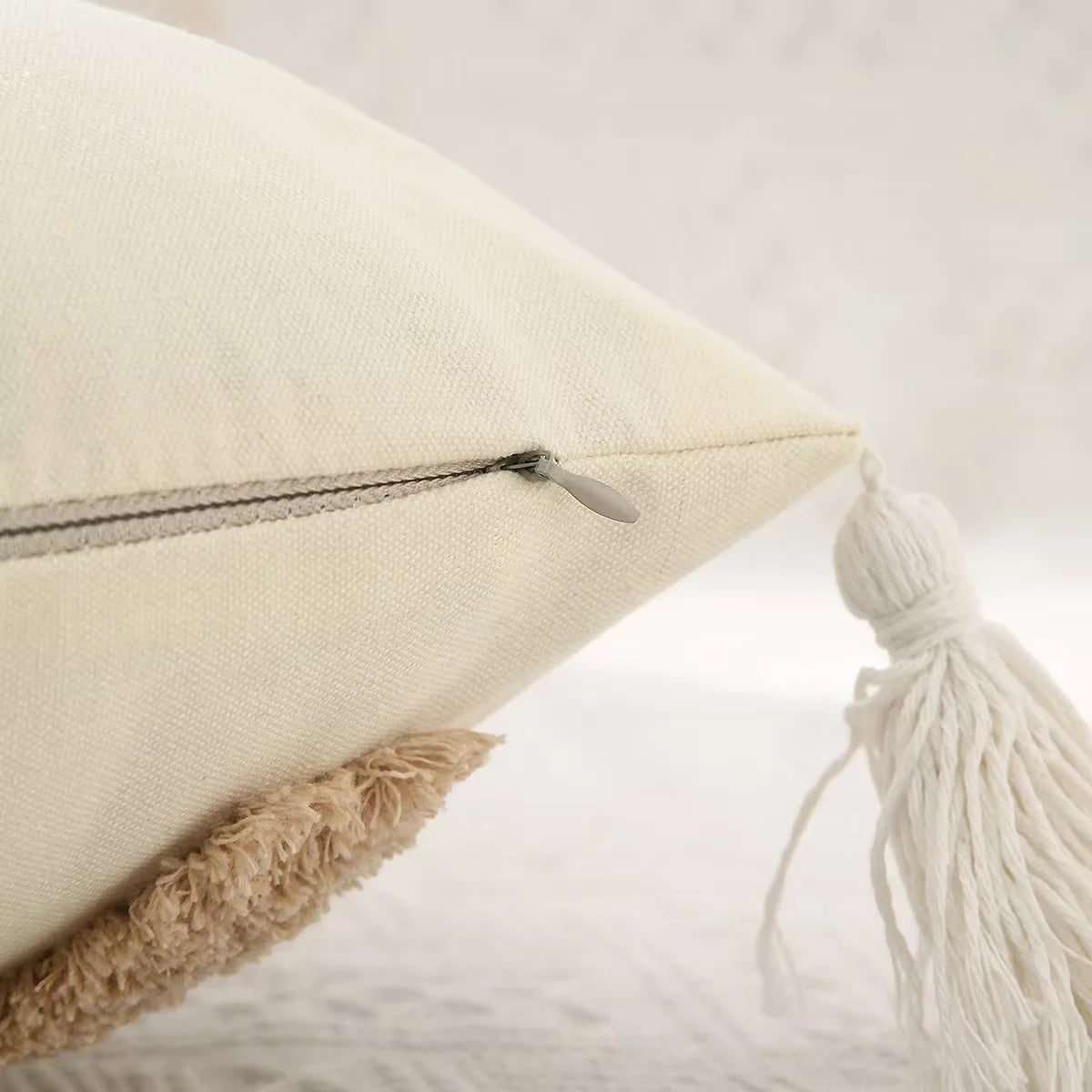 Close-up of a beige pillow with a tassel on a light background Nordic Bohemian geometric plush pillow cover with embroidered design and tassels, perfect for boho home decor on sofa, bed, or accent chair β cozy neutral cushion cover for living room or bedroom style