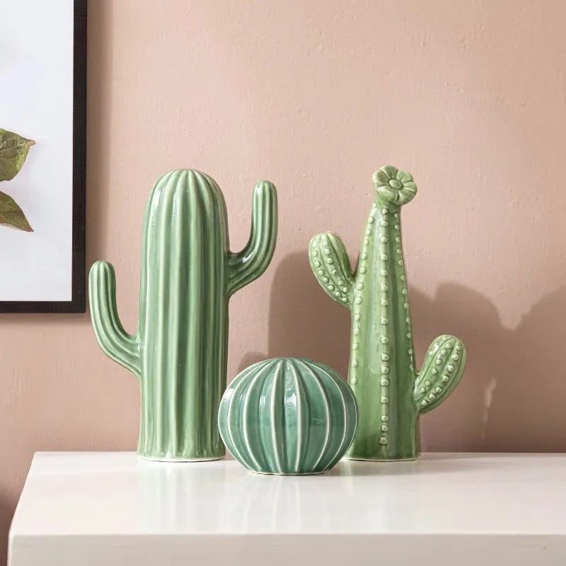 Three green cactus-shaped vases on a white surface with a pink wall background. Boho Nordic cactus decor prop for photography and interiors