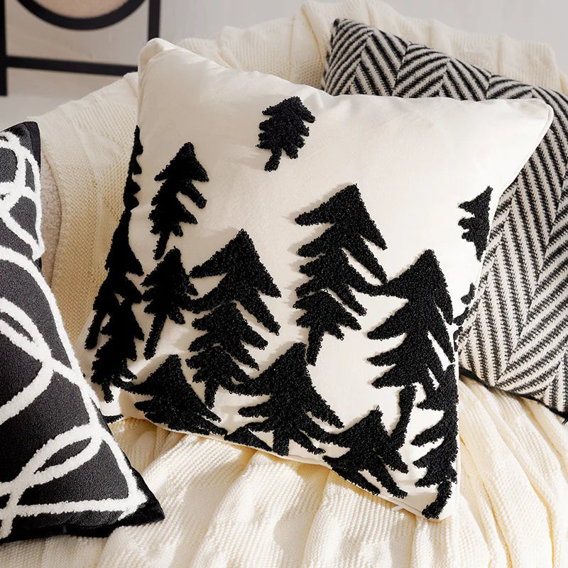 Decorative pillows with black xmas tree patterns on a neutral background