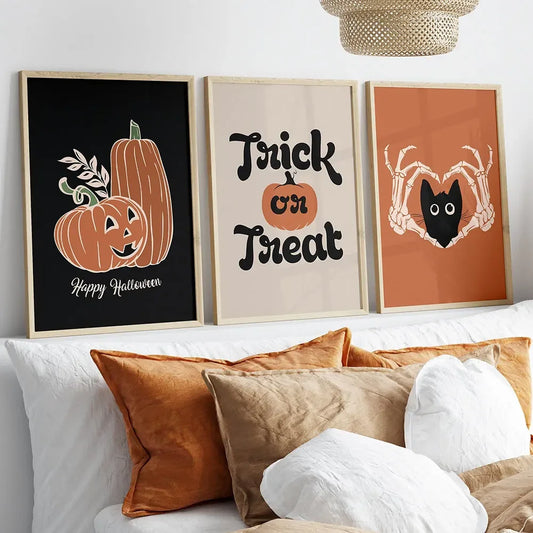 Three Halloween-themed framed pictures on a wall above a sofa with decorative pillows. Halloween cat and pumpkin canvas wall art, ghost cat and jack-o'-lantern print on cotton canvas, spooky cute autumn home decor for living room or kitchen.