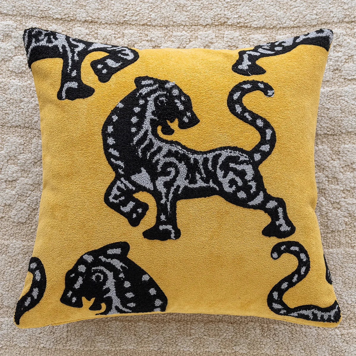 Yellow pillow with black tiger design on a beige carpet. embroidery throw pillow cover in boho modern style