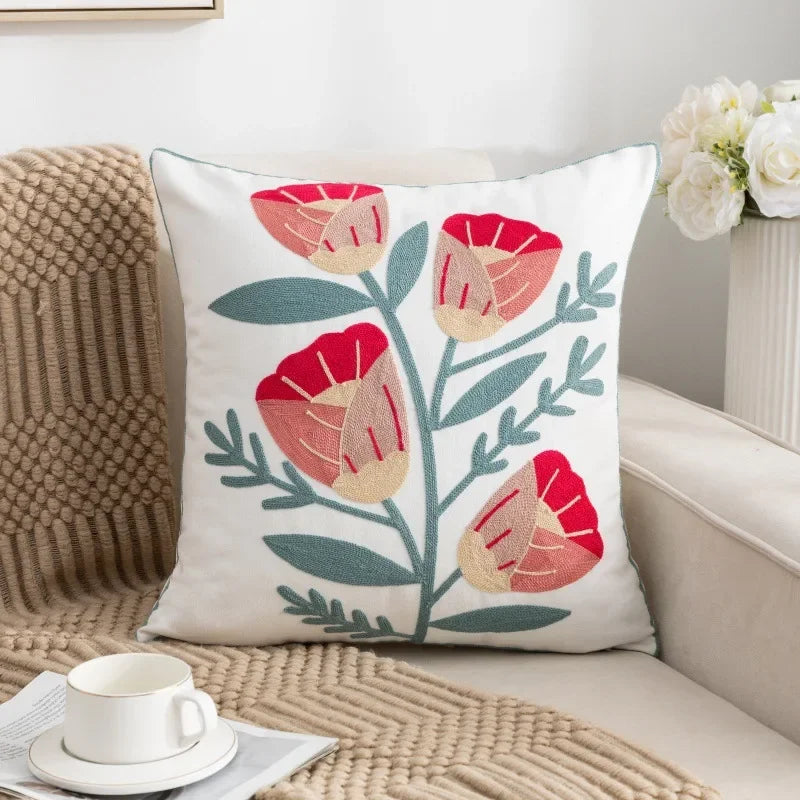 Decorative pillow with floral design on a couch next to a cup of coffee Embroidered flower pillow cover, 17.7-inch square canvas cushion case with floral design for sofa, bed, and boho home decor