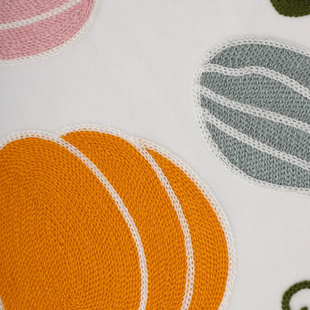 Close-up of fabric with circular patterns in orange, pink, gray, and green on a white background.